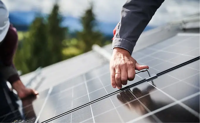 太陽光パネルに手を添える作業員