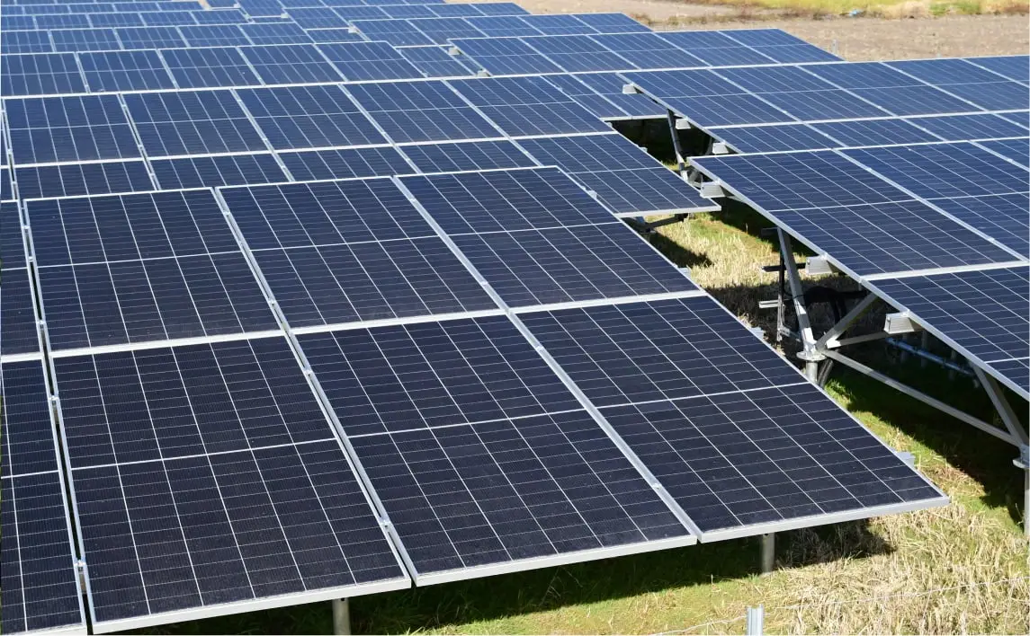 青空の下、複数の列に整然と並ぶ太陽光パネルが広がるソーラーファーム