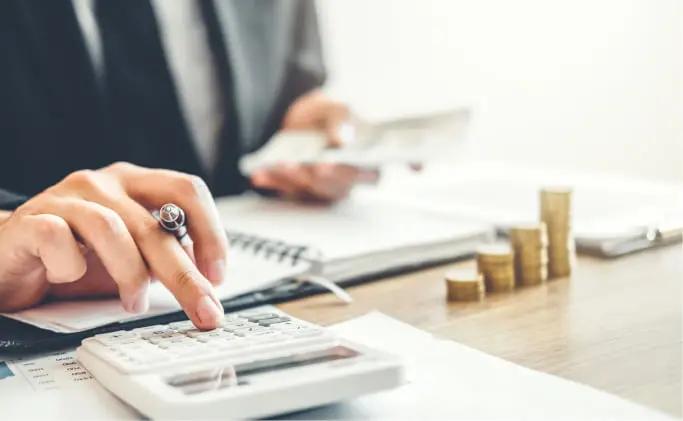 電卓で費用計算をするビジネスパーソンとコイン